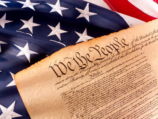 The words We the People from the U.S. Constitution, lying on an American flag